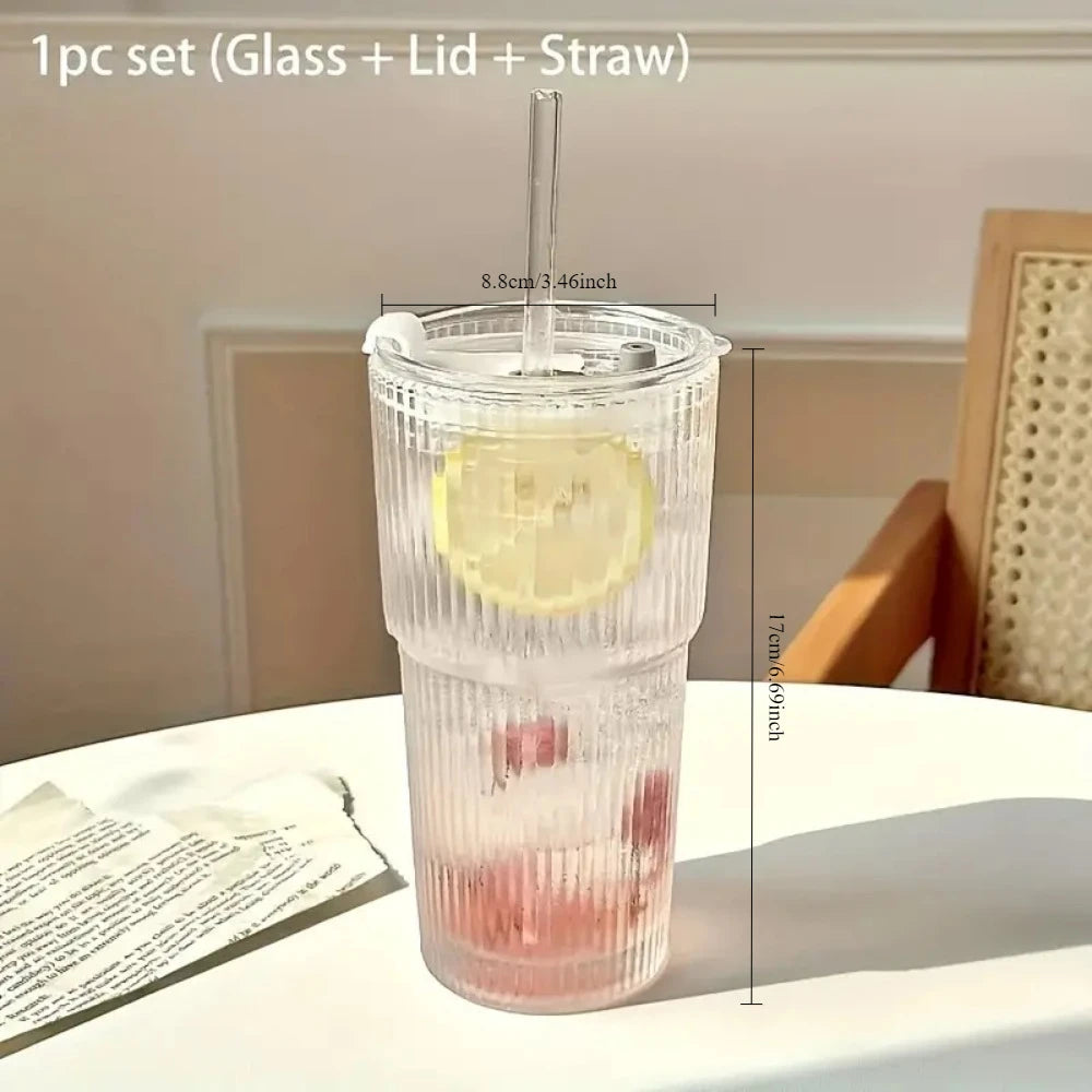 Clear glass tumbler with lid and straw on a table with lemon and strawberry slices.